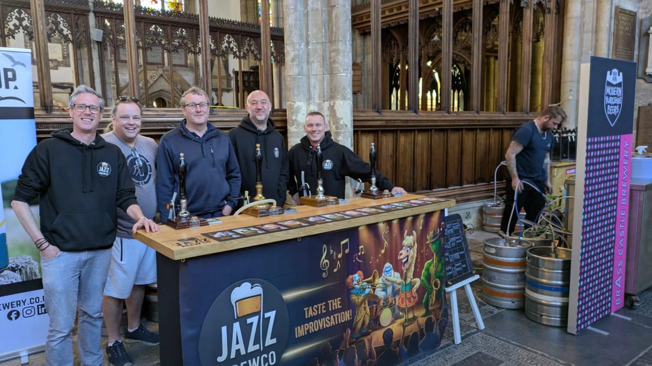 Five of the Jazz BrewCo team behind their festival bar with kegs and pump clips